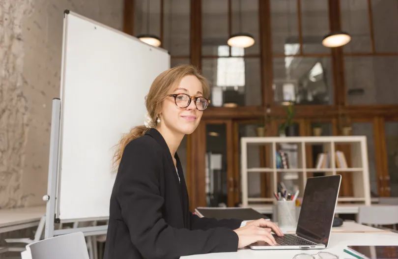 Jeune femme portant des lunettes, profession libérale, en plein travail sur son ordinateur